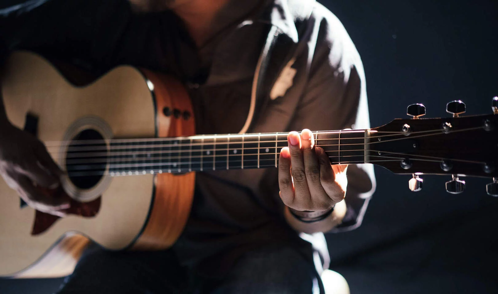 Nahaufnahme einer Person, die Akustikgitarre spielt und einen Palm Mute ausführt.